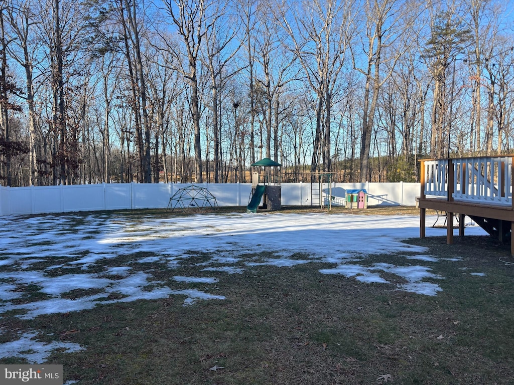 yard covered in snow featuring a playground