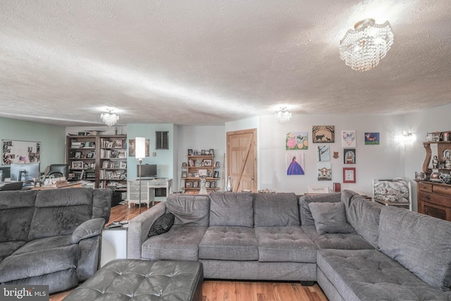 living room featuring wood-type flooring, a notable chandelier, and a textured ceiling