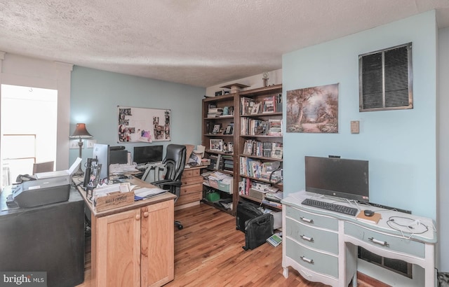 office area with light wood-type flooring and a textured ceiling