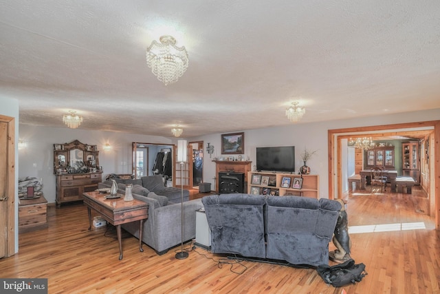 living room with a chandelier, a textured ceiling, and light hardwood / wood-style floors