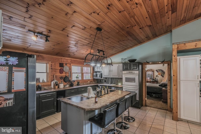 kitchen with light tile patterned floors, appliances with stainless steel finishes, a kitchen breakfast bar, vaulted ceiling, and a kitchen island