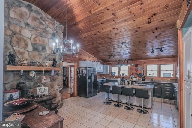 kitchen featuring black refrigerator with ice dispenser, a kitchen bar, light tile patterned flooring, gray cabinetry, and wooden ceiling