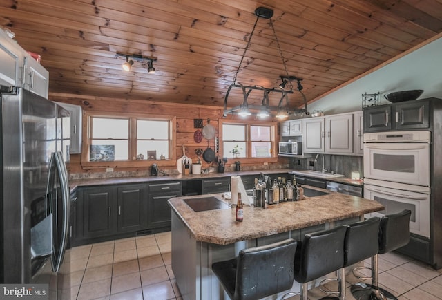 kitchen featuring stainless steel appliances, a center island, a kitchen breakfast bar, lofted ceiling, and sink