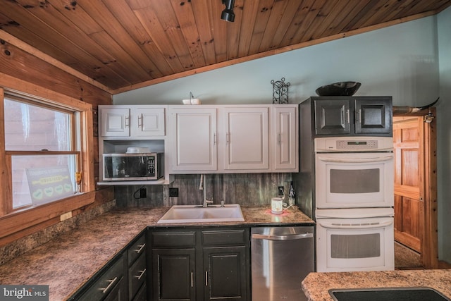 kitchen featuring white cabinetry, appliances with stainless steel finishes, backsplash, lofted ceiling, and sink