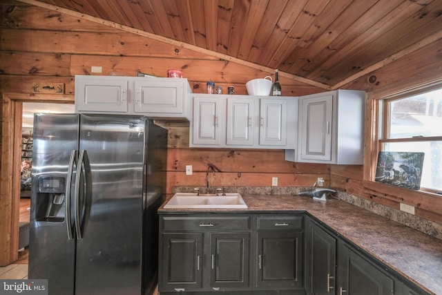 kitchen featuring stainless steel refrigerator with ice dispenser, white cabinetry, and wooden walls