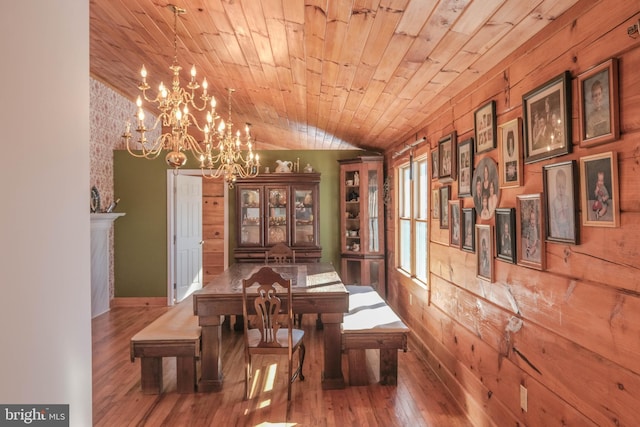 dining space with an inviting chandelier, hardwood / wood-style floors, wooden walls, wooden ceiling, and lofted ceiling