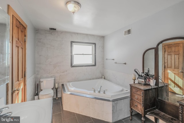 bathroom with tiled bath, sink, tile patterned floors, and toilet