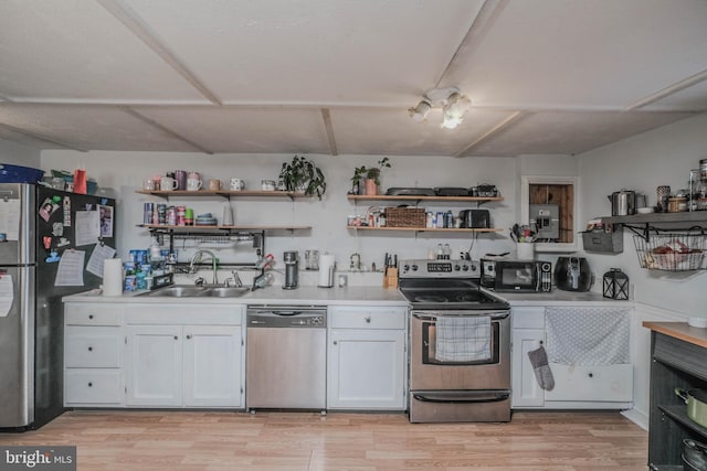 kitchen with white cabinets, appliances with stainless steel finishes, sink, and light hardwood / wood-style floors