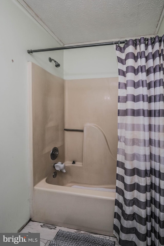 bathroom with a textured ceiling and shower / tub combo