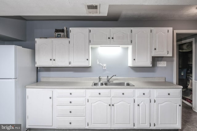 kitchen featuring sink, white cabinetry, and white refrigerator