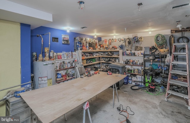 misc room featuring concrete floors, electric water heater, and a workshop area