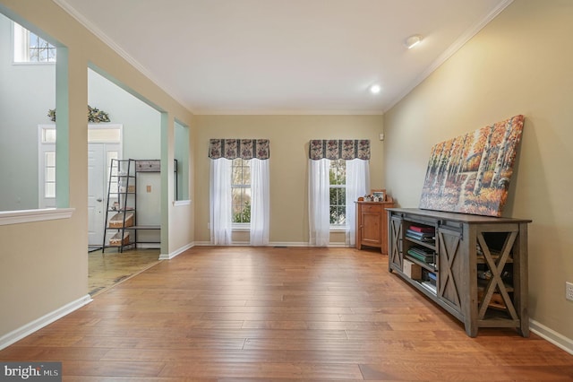 interior space with baseboards, wood finished floors, and crown molding