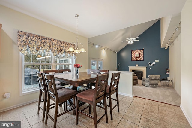 dining room featuring light tile patterned floors, a fireplace, a ceiling fan, baseboards, and vaulted ceiling