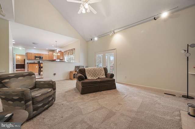 living area with high vaulted ceiling, rail lighting, light carpet, and baseboards