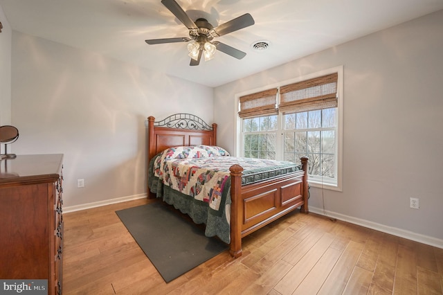 bedroom with light wood finished floors, baseboards, visible vents, and a ceiling fan