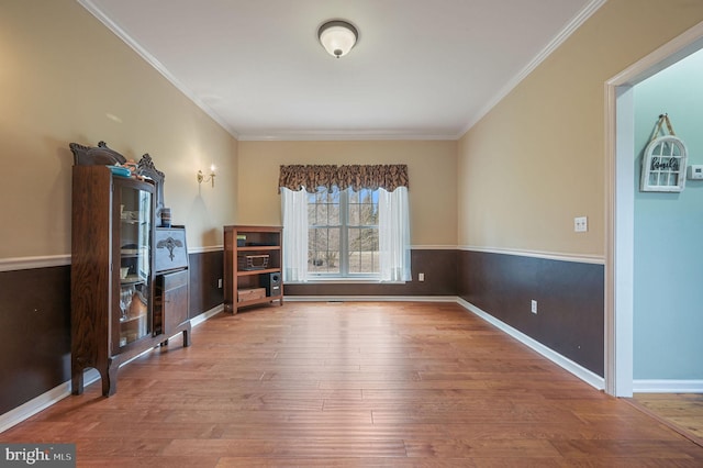 interior space with baseboards, ornamental molding, and wood finished floors