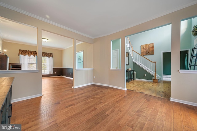 unfurnished living room with baseboards, stairway, wood-type flooring, and crown molding