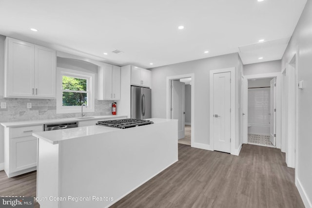 kitchen with light hardwood / wood-style floors, a kitchen island, white cabinetry, appliances with stainless steel finishes, and sink