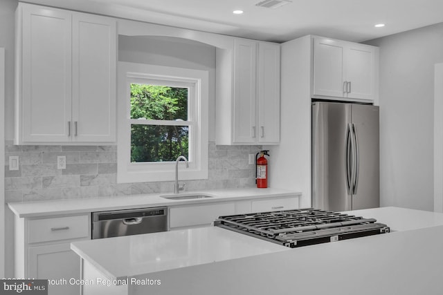 kitchen with stainless steel appliances, white cabinets, and sink