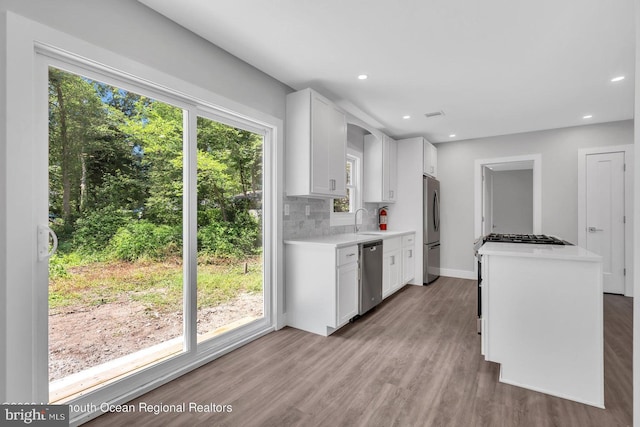 kitchen featuring light hardwood / wood-style flooring, backsplash, white cabinetry, appliances with stainless steel finishes, and sink