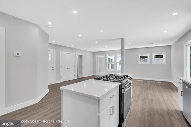 kitchen with a kitchen island, white cabinets, light hardwood / wood-style flooring, and appliances with stainless steel finishes