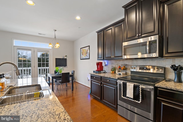 kitchen with pendant lighting, dark wood-type flooring, stainless steel appliances, decorative backsplash, and sink