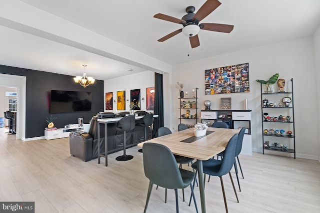 dining space with ceiling fan with notable chandelier and light hardwood / wood-style flooring