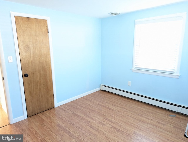 spare room with baseboard heating and light hardwood / wood-style flooring