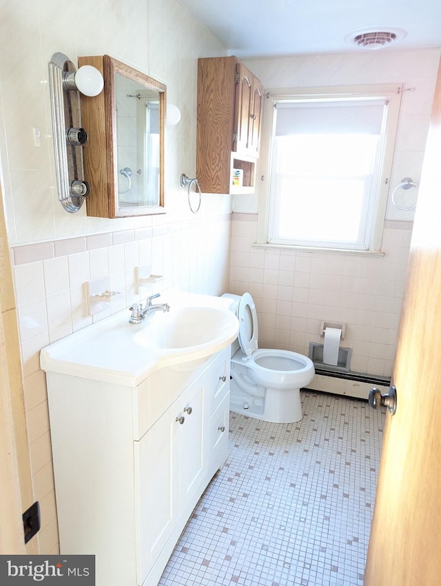 bathroom with tile walls, a baseboard heating unit, tile patterned floors, and vanity