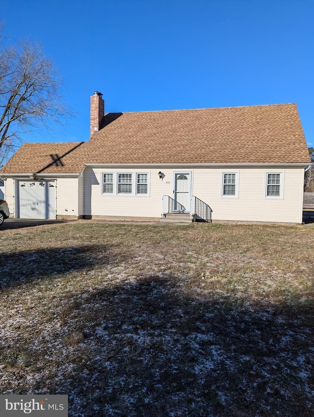 back of house featuring a lawn and a garage