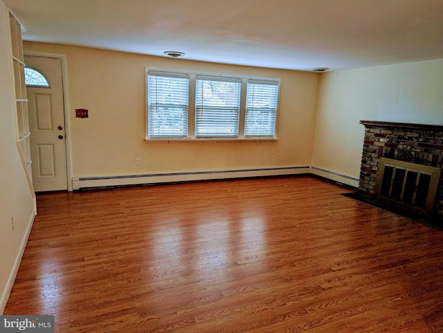 unfurnished living room featuring a brick fireplace, a baseboard heating unit, and hardwood / wood-style floors