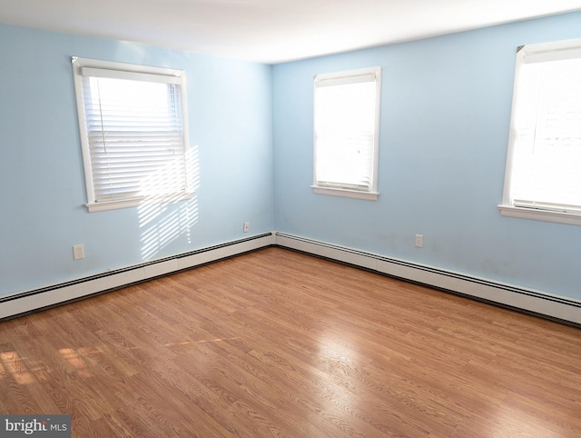 empty room with light hardwood / wood-style floors, a healthy amount of sunlight, and a baseboard radiator