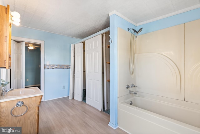 bathroom featuring bathing tub / shower combination, ceiling fan, wood-type flooring, vanity, and crown molding