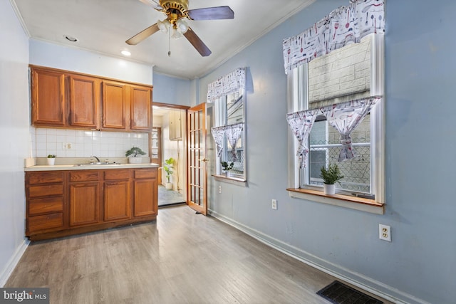 kitchen featuring sink, ceiling fan, light hardwood / wood-style floors, ornamental molding, and decorative backsplash