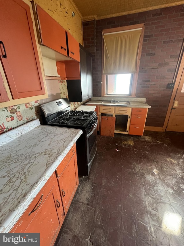 kitchen featuring sink, brick wall, and stainless steel range with gas stovetop