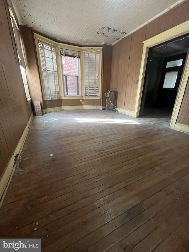 empty room with dark hardwood / wood-style flooring, wooden walls, and wooden ceiling