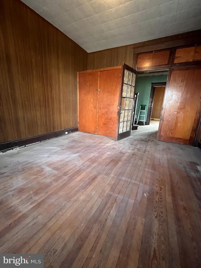 spare room with light hardwood / wood-style flooring and wooden walls