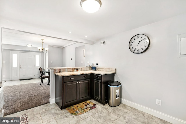 kitchen with a chandelier, dark brown cabinetry, kitchen peninsula, and hanging light fixtures