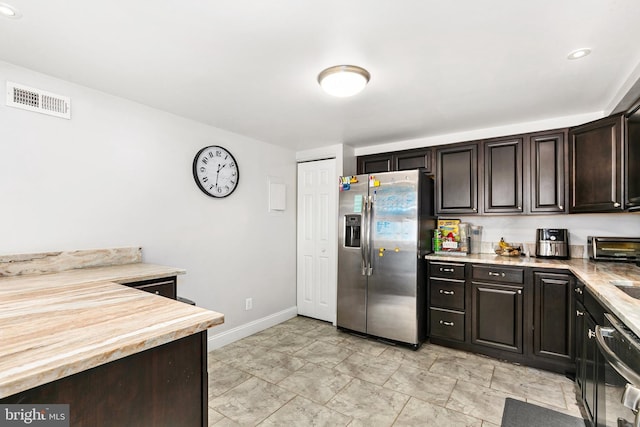 kitchen featuring dishwasher, dark brown cabinets, and stainless steel fridge