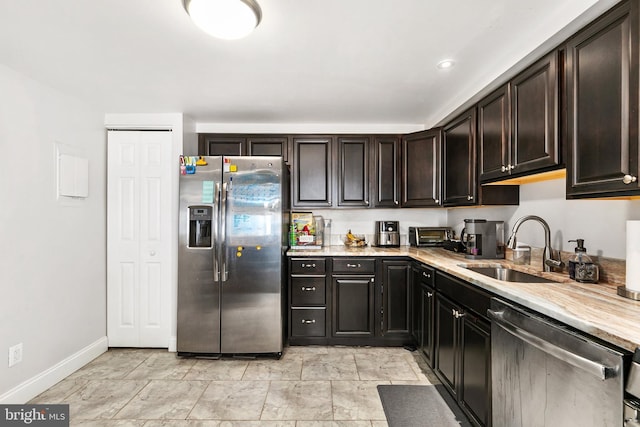 kitchen with stainless steel appliances, light stone countertops, sink, and dark brown cabinetry