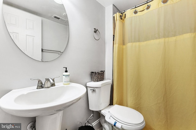 bathroom with a shower with curtain, sink, and toilet