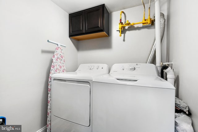 laundry area with washing machine and dryer and cabinets