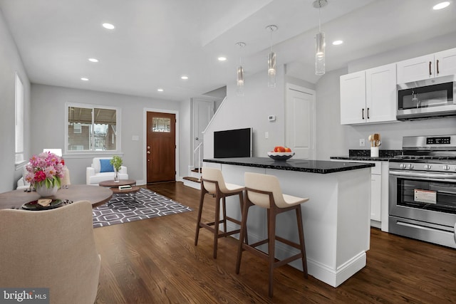 kitchen featuring dark hardwood / wood-style floors, white cabinetry, appliances with stainless steel finishes, and a center island