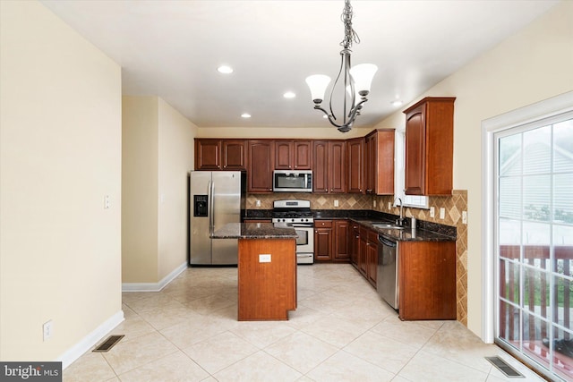 kitchen with backsplash, a center island, stainless steel appliances, dark stone counters, and a chandelier