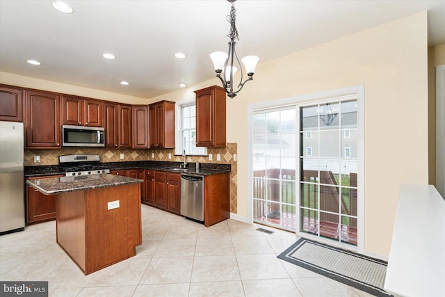 kitchen featuring decorative light fixtures, a notable chandelier, a center island, sink, and appliances with stainless steel finishes