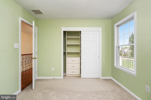 unfurnished bedroom featuring light colored carpet, multiple windows, and a closet