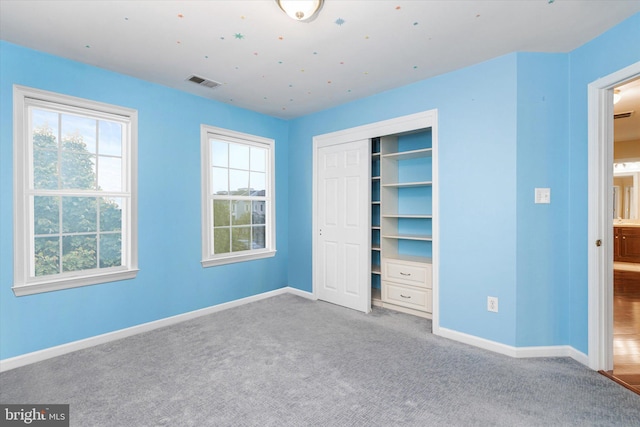 unfurnished bedroom with carpet floors, multiple windows, and a closet