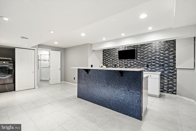 kitchen featuring a breakfast bar area, white cabinetry, and washer / clothes dryer