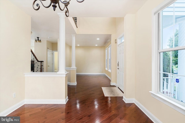 corridor featuring ornate columns, dark hardwood / wood-style flooring, and plenty of natural light