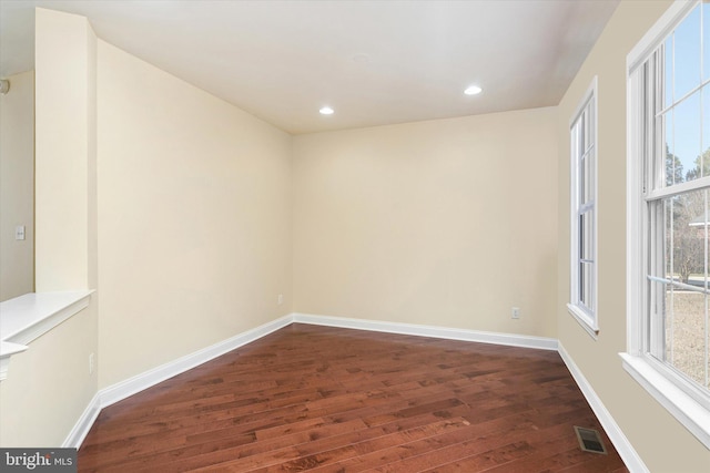 spare room featuring dark wood-type flooring and plenty of natural light